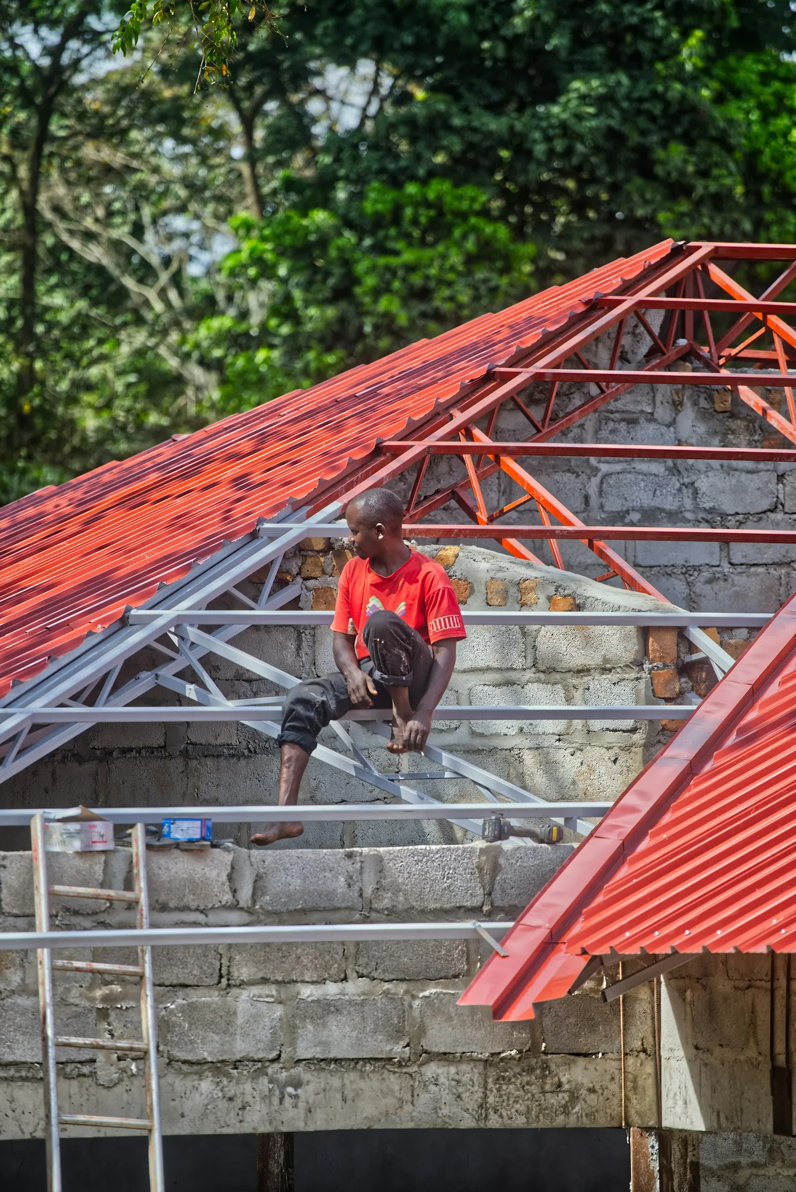 Pekerja memasang genteng metal merah baru pada rangka atap di Bogor Timur